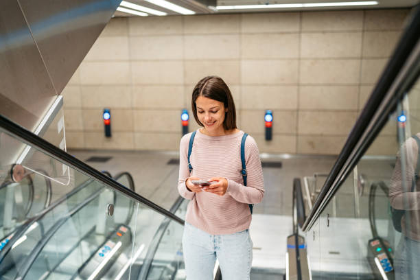 istock Young Woman Using A Phone While Riding An Escalator In A Subway Station In Copenhagen In Denmark 1994703042