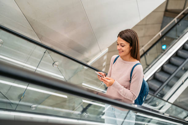 istock Young Woman Using A Phone While Riding An Escalator In A Subway Station In Copenhagen In Denmark 1994706715