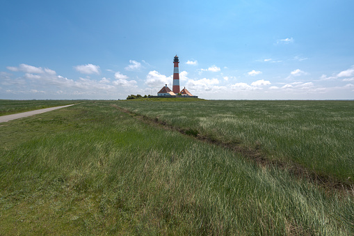 A Westerhever Lighthouse standing tall in a sunny field, Baltic Sea, Germany