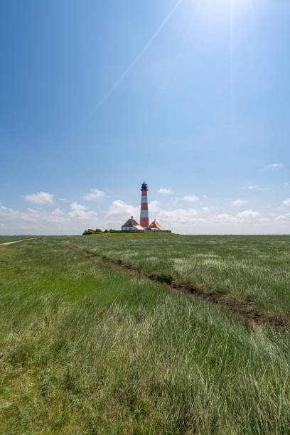istock Westerhever Lighthouse standing tall in a sunny field, Baltic Sea, Germany 1994717828