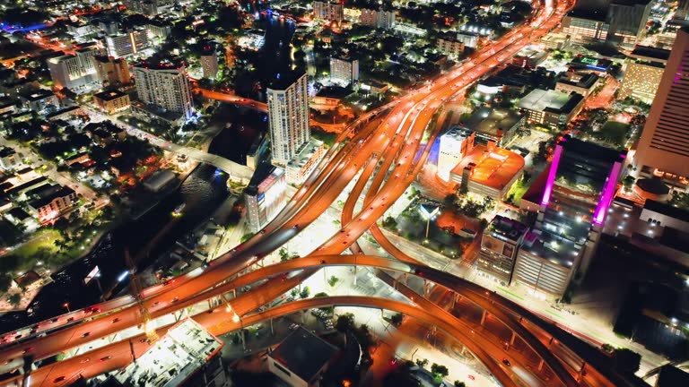 Aerial view of freeway intersection at night with fast driving cars and trucks in Miami city, Florida. Transportation infrastructure.