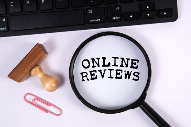 istock Online Reviews. Magnifying glass and computer keyboard on white office table 1994761790