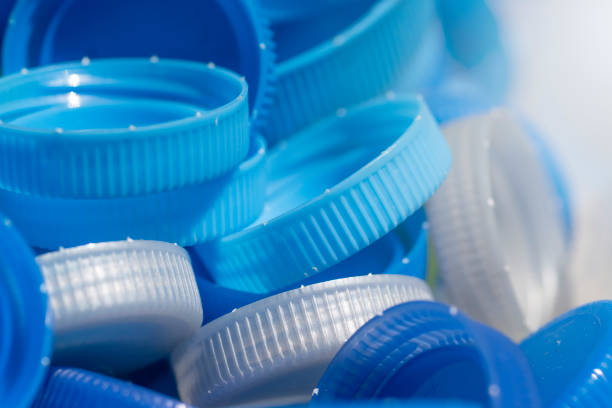 gros plan sur des couvercles en plastique bleu et gris ou des bouchons de bouteilles d’eau potable à recycler sur le verre. - packaging recycling bottle plastic photos et images de collection