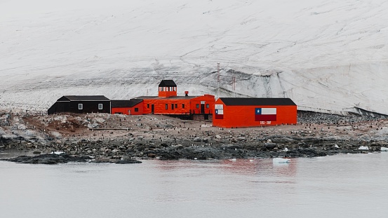 Antarctica Scientific Research Station at the coast of King George Island in front of huge Glacier. Vibrant orange-red painted SResearch Station and Rescue Huts and Houses at the Coast towards the Antarctic Ocean, Dallmann Bay, King George Island - Melchior Islands, Antarctica