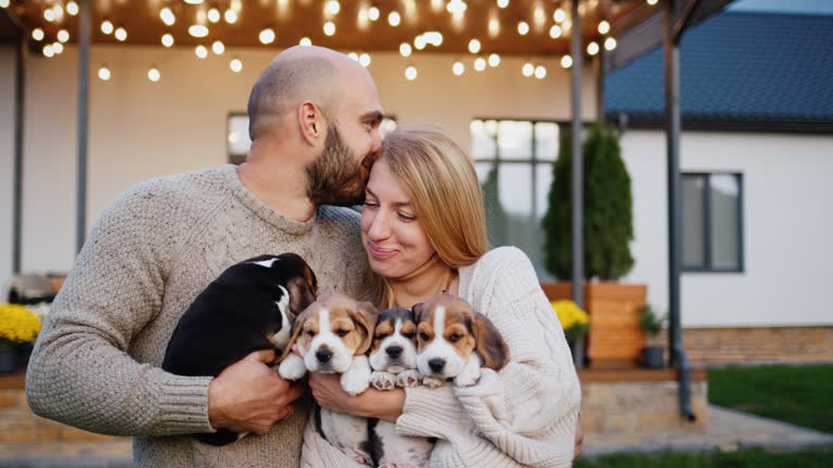 Portrait of a happy young couple with puppies. Standing in front of their beautiful home