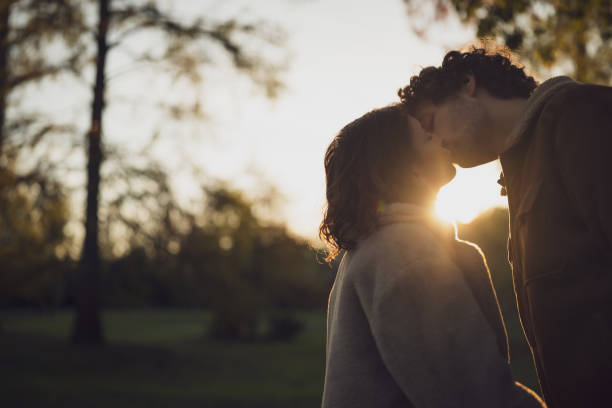 loving couple - silhouette kissing park sunset imagens e fotografias de stock