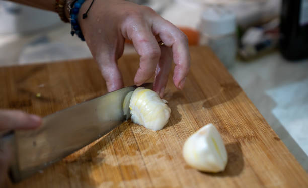 istock Person expertly dicing a fresh white onion on a rustic wooden cutting board 1994792759