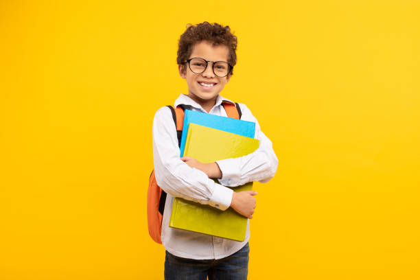 istock Nerdy boy with glasses holding books, orange backpack 1994798617