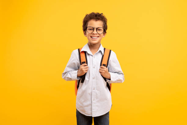 istock Happy schoolboy with backpack and glasses, yellow background 1994798984