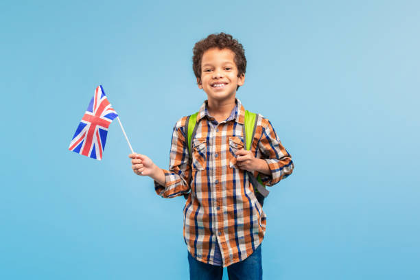 istock Smiling child boy with UK flag, backpack, blue background 1994799147