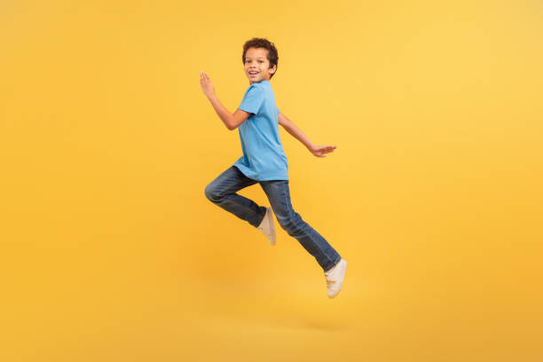 istock Black boy in mid-run on bright yellow background 1994799161