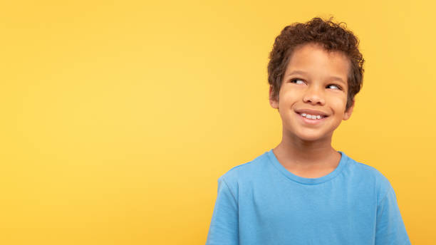 istock Thoughtful smiling boy looking up at free space on yellow background 1994799681