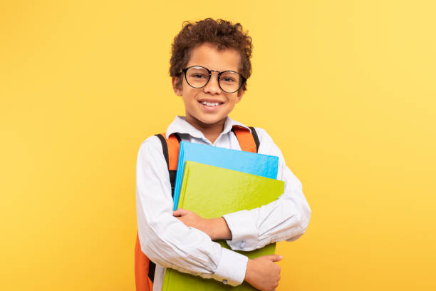 istock Smiling student with glasses and folders on yellow background 1994799692