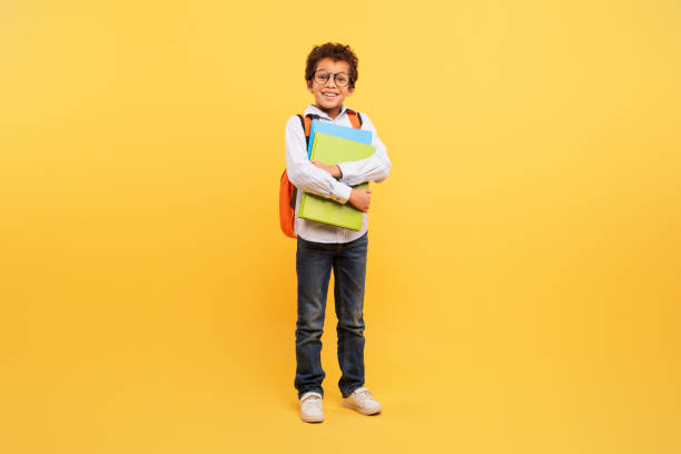 istock Smiling schoolboy with folders on sunny yellow background 1994799693