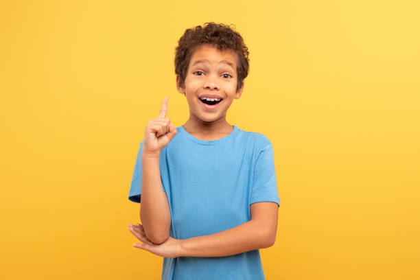 istock Excited boy with idea, finger raised up on yellow background 1994799694
