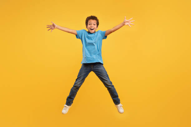 istock Joyful boy jumping, light blue shirt, full length 1994799713