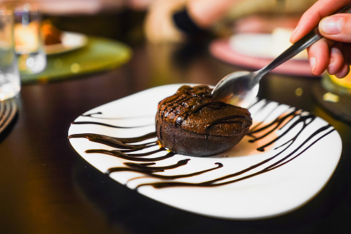 A spoon delving into a molten chocolate cake on a decorated plate.