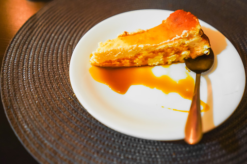 A slice of cheesecake with caramel sauce on a white plate.