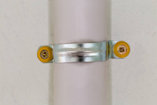 Plastic pipe, as duct for pulling of communication cables fixed to a concrete wall with metal pipe clamp and screws indoor