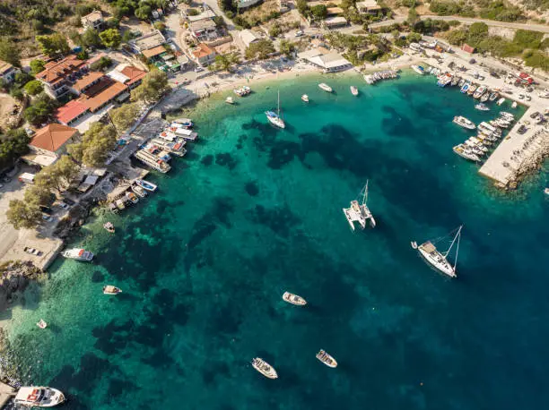 Photo of Port on a Greek island with blue turquoise water with many boats and yachts on the water in Greece, Zakynthos. Aerial drone photo of Agios Nikolaos - a small port on the island of Zante.