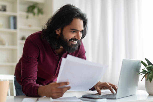 istock Focused indian man analyzing documents and working on his laptop at home 1994830076
