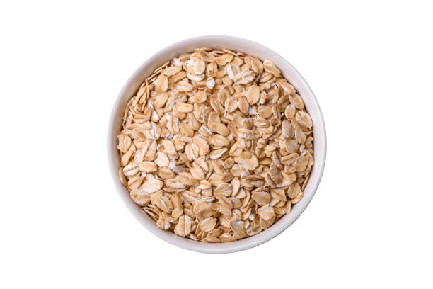 istock Raw oatmeal flakes in a ceramic bowl on a dark concrete background 1994834482