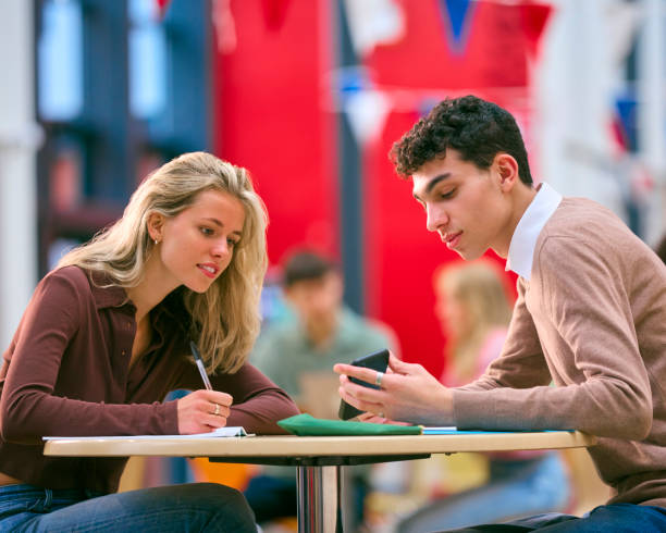 istock Two College Or University Students With Mobile Phone Working Together In Study Area 1994849718