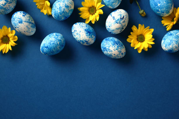 istock Frame border of blue and white Easter eggs on dark blue background with yellow flowers. Flat lay, top view, copy space. 1994854533