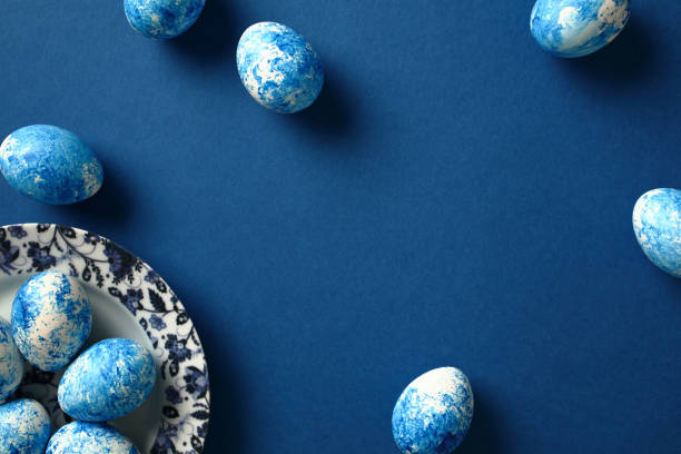 istock Modern minimal blue and white Easter eggs with gzhel porcelain plate on dark blue background. Flat lay, top view, copy space. 1994855086