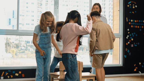 istock Diverse children playing musical chairs while teacher turn off music. Erudition. 1994864729