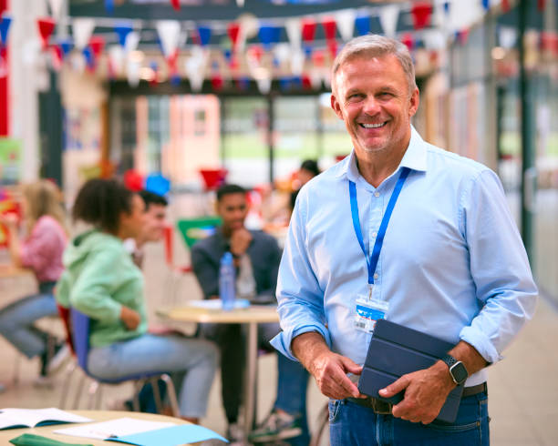 istock Smiling Male University Teacher Tutor Or Lecturer Inside College Building With Digital Tablet 1994866877
