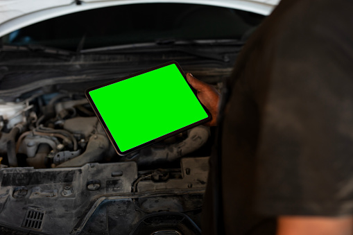 Mechanic using tablet checking up on car engines parts for fixing and repair