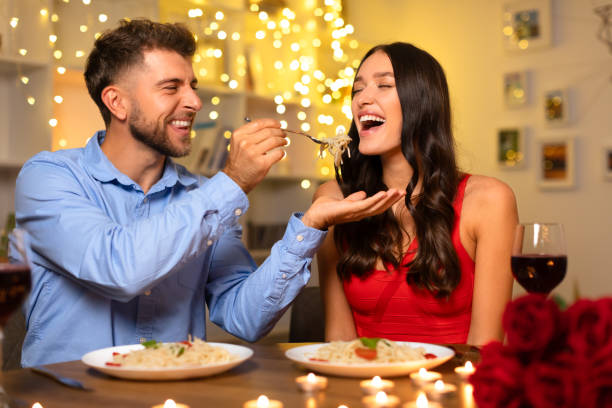 istock Joyful man feeding pasta to laughing woman during romantic dinner 1994892961
