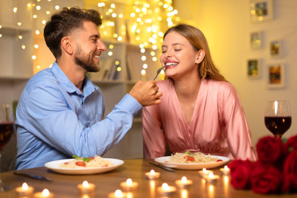 istock Man feeding woman pasta on romantic date 1994894129