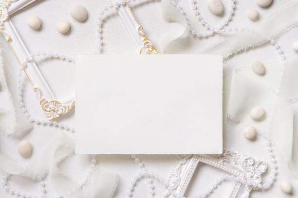 istock Blank card near white decorations, pebbles and silk ribbons top view, wedding menu mockup 1994906150