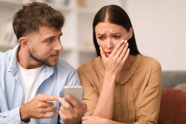 istock Jealous husband checking wife's smartphone reveals infidelity at home 1994912387