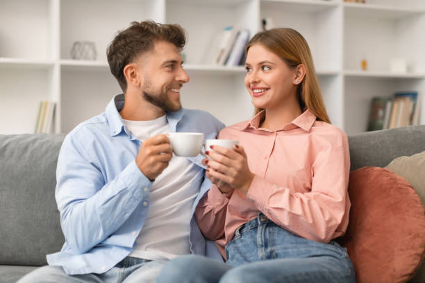 istock Young couple in love drinking tea sitting on sofa indoors 1994912416