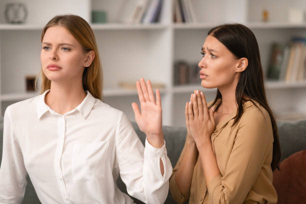 Woman Gesturing Stop In Refusal To Friend Begging Favor Indoor Woman Saying No and Gesturing Stop In Refusal To Friend Begging For Favor Or Forgiveness After Quarrel, Sitting On Couch In Modern Living Room Interior. Friendship Relationship Problems indifference stock pictures, royalty-free photos & images
