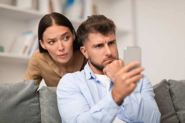 istock wife glancing at husband's smartphone while he texting at home 1994912472