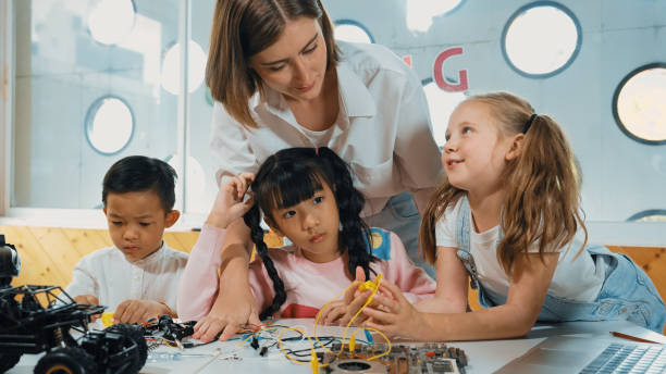 istock Teacher looking at children while diverse student looking at screen. Erudition. 1994929026