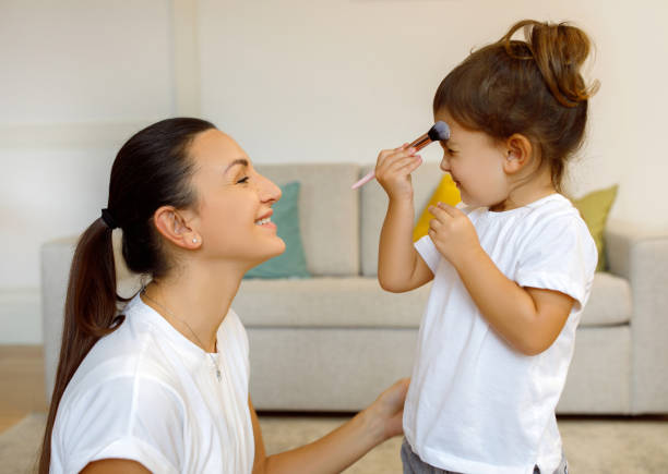 istock Small girl with makeup brush at home, having fun with mom 1994947706