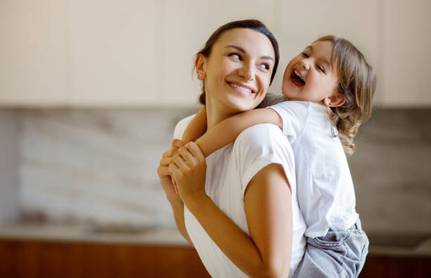 istock Laughing child embracing her joyful mother while they playing together at home 1994947720