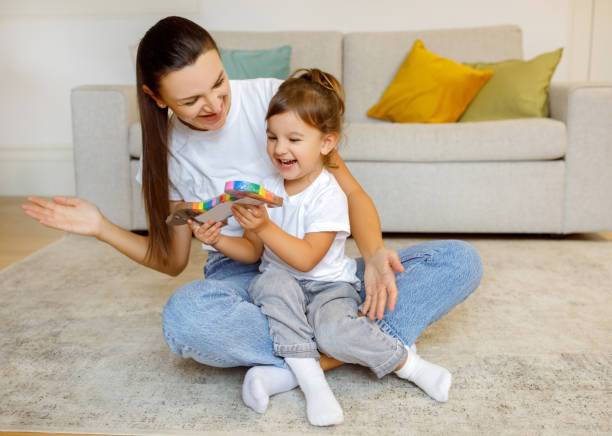 istock Mother and little child laughing while playing with toy at home 1994948270