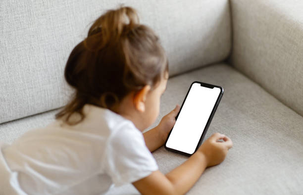 Little Girl Lying On Couch And Using Blank Smartphone With White Screen