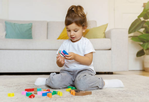 menina brincando com blocos coloridos enquanto está sentada no chão em casa - sorter - fotografias e filmes do acervo