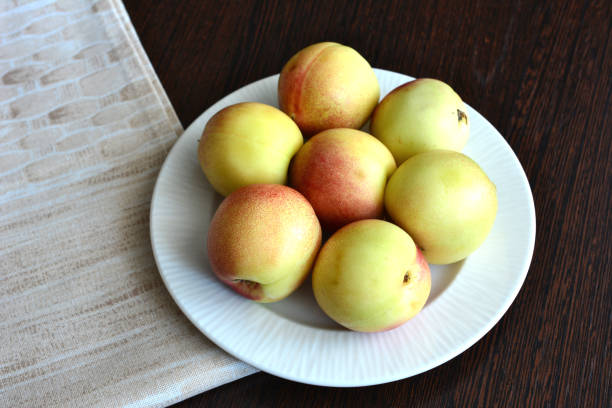 yellow nectarines on the white plate on the table top view