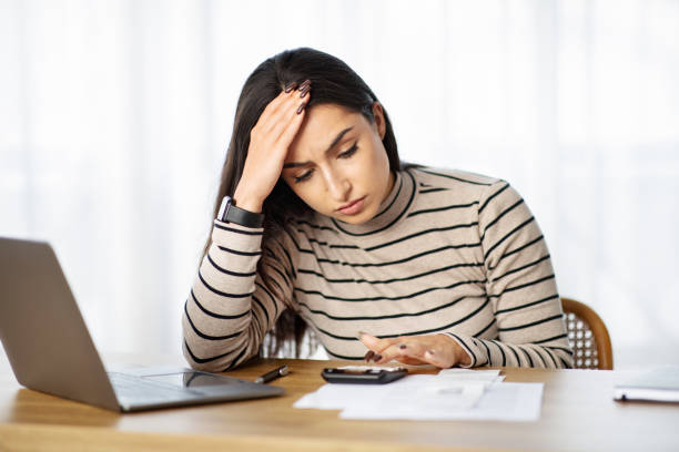 istock A concerned young woman with a smartwatch holds her forehead in worry 1994971253