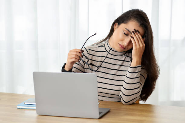 istock An exhausted young woman holding her eyeglasses feels a headache 1994971256