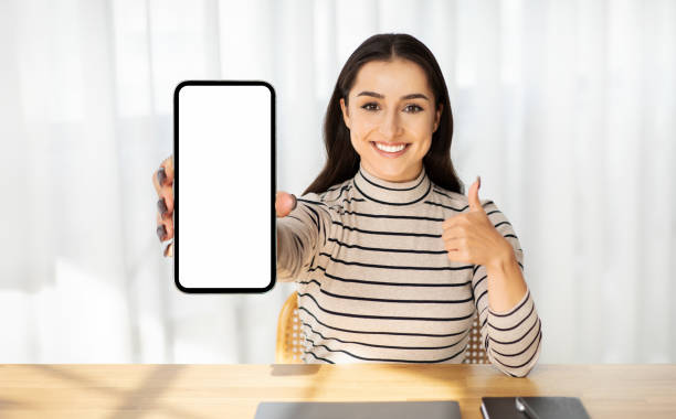 istock Millennial smiling arab lady show phone with blank screen, show thumb up gesture 1994971267