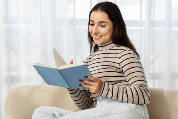 istock Cheerful calm millennial caucasian lady read book, planning day, work, sit at sofa 1994971783